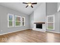 Spacious living room with a painted fireplace, wood floors, ceiling fan, and bright natural light at 9385 Helmsdale Dr, Indianapolis, IN 46256