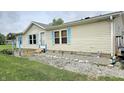Single-story home featuring light siding, blue shutters, and decorative garden gnomes along the front flower bed at 10694 W Hickory Ct, Quincy, IN 47456