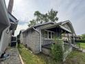Side view of a stone house showing the yard, windows, and roofline at 1214 Wallace Ave, Indianapolis, IN 46201
