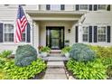 Inviting front porch adorned with lush greenery and an American flag welcomes guests to this beautiful home at 12234 Limestone Dr, Fishers, IN 46037
