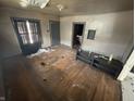 Shows an unkept living room with hardwood floors and dated trim, and a peak into the next room at 1226 Hiatt St, Indianapolis, IN 46221