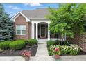Cozy front porch with white columns and colorful landscaping at 15410 Mission Hills Dr, Carmel, IN 46033