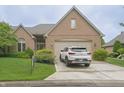 Charming brick home featuring a well-manicured lawn, lush shrubbery, and a two-car garage with car in the driveway at 1870 Broadleaf Ct # 10, Greenwood, IN 46143