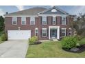 Inviting brick home featuring a well-maintained lawn, lush landscaping, and an attached two-car garage at 21491 Raccoon Ct, Noblesville, IN 46062