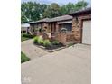 Brick home featuring a paved walkway, landscaped garden beds and an attached garage at 3130 Taylor Rd, Columbus, IN 47203