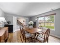 Cozy dining room with wood floors, a neutral color scheme, bright windows, and a view of the home's staircase at 317 Virginia St, Fortville, IN 46040