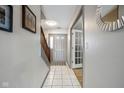 Bright hallway with neutral walls, tiled floor, stairs, and doorway featuring a white door with window panes at 317 Virginia St, Fortville, IN 46040