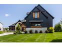 Picture of a stylish home featuring a blend of dark wood and light stone, enhanced by a green lawn at 3675 Dartmoor Way, Zionsville, IN 46077