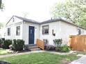 Quaint home featuring fresh landscaping, new wooden fencing, and a welcoming blue front door at 4445 Kingsley Dr, Indianapolis, IN 46205