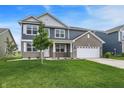 Charming two-story home featuring gray siding, brick details, white trim, a well-kept lawn, and an attached garage at 5812 Flat Hill Dr, Indianapolis, IN 46239