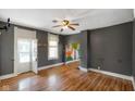 Living room with ceiling fan, dark grey painted walls, wood floors, and dinosaur art at 590 W Washington St, Martinsville, IN 46151