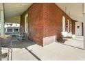 Covered porch has painted brick, chairs, hanging swing, and ceiling fan at 590 W Washington St, Martinsville, IN 46151
