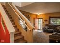 Inviting living room showcasing a carpeted staircase, neutral decor, and a comfortable gray sofa near the door at 6585 Dunsdin Dr, Plainfield, IN 46168