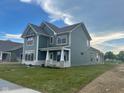Inviting two-story home featuring a covered porch, green siding, and a well-manicured lawn at 13646 Grand Abbey Way, Fishers, IN 46037