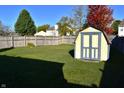 Fenced backyard with lush green grass and a small storage shed with painted doors at 1896 Central Park W Blvd, Greenwood, IN 46143