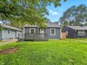 Quaint home with a front porch, fresh green grass, and leafy trees overhead at 3422 Hillside Ave, Indianapolis, IN 46218