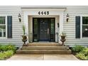 Elegant front entrance featuring a black door, stylish lanterns, decorative planters, and well-maintained landscaping at 4443 Mallard Pt, Columbus, IN 47201