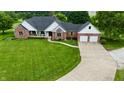 Beautiful exterior elevation of brick home featuring manicured lawn, mature landscaping, and concrete driveway leading to attached garage at 4670 N 600 E, Franklin, IN 46131