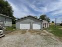 A detached two-car garage with white doors, accompanied by a small garden shed, offering ample storage at 4673 S 400 W, New Palestine, IN 46163
