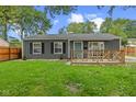 Charming gray home with a wooden porch, well-maintained lawn, and dark shutters on the windows at 5367 Penway St, Indianapolis, IN 46224
