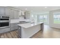 Open kitchen featuring gray cabinets, a large island, stainless steel appliances, and hardwood floors at 5673 Stetson Dr, Whitestown, IN 46052