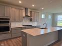 Bright kitchen boasts modern gray cabinets, stainless steel appliances, and a large center island with quartz countertop at 5673 Stetson Dr, Whitestown, IN 46052
