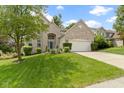 Charming brick home with an attached two-car garage and a well-maintained green lawn at 5857 Stone Pine Trl, Carmel, IN 46033