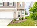 Home's inviting front entrance features a glass-paneled door, mulched flower bed, and well-kept lawn at 10210 Samerton Ln, Indianapolis, IN 46239