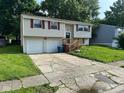 Split-level home featuring attached two-car garage and inviting front yard with mature landscaping at 10316 Woodhaven Cir, Indianapolis, IN 46229