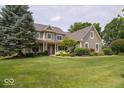 Traditional two-story home with verdant lawn, beautiful landscaping and inviting front porch at 10865 Fairwoods Dr, Fishers, IN 46037