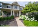 Covered front porch with white columns, a charming seating area, and lush landscaping at 10865 Fairwoods Dr, Fishers, IN 46037