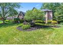 Two-story brick home featuring landscaped front yard with green grass and mature shade trees at 11266 Old Stone Dr, Indianapolis, IN 46236