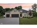 Beautiful light brick home with well-manicured lawn and a spacious attached two-car garage at dusk at 14729 Erica Ln, Carmel, IN 46033