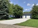 Charming blue home featuring a spacious two-car garage and a pristine white gravel driveway at 221 N 9Th St, Elwood, IN 46036