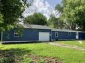 Rear exterior showcasing the home's blue siding, well-maintained yard, and attached garage for ample parking at 221 N 9Th St, Elwood, IN 46036