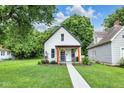 Charming bungalow featuring a walkway to the porch, lush green lawn, and updated black trim at 3035 Guilford Ave, Indianapolis, IN 46205