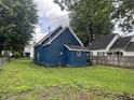Exterior shot of the rear of a blue home with a spacious backyard and chain-link fence at 3127 E Lynn St, Anderson, IN 46016