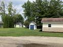 View of backyard with several storage buildings with siding matching house at 321 S 23Rd St, Elwood, IN 46036