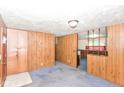 Cozy living area with paneled walls, carpet, and entry to kitchen or dining at 3965 Alsace Pl, Indianapolis, IN 46226