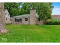 View of front yard featuring stone chimney, large green lawn, and small front porch at 508 W 38Th St, Indianapolis, IN 46208