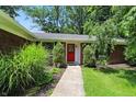 Inviting front entrance with a red door, neat landscaping, and a walkway to the house at 7736 Wawasee Dr, Indianapolis, IN 46250