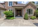 Close-up of the front door with brick exterior, mature landscaping, and charming wreath at 10455 Trewithen Ln, Carmel, IN 46032