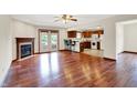 Open-concept living room with hardwood floors, fireplace, ceiling fan, and a seamless connection to the kitchen at 177 Jacinta Pl, Bargersville, IN 46106