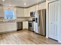 Bright kitchen with white cabinets, stainless steel appliances, and laminate flooring at 213 Drewood Dr, Trafalgar, IN 46181
