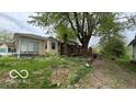 The backyard is spacious, with a brick chimney and a large tree providing shade at 252 Ringwood Way, Anderson, IN 46013