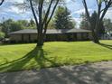 Traditional ranch-style home with a lush green lawn and mature trees, offering a serene and inviting curb appeal at 2937 S Allen Dr, New Palestine, IN 46163
