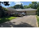 Well-maintained single-story brick home with an attached garage and a driveway, surrounded by lush greenery at 3440 W 46Th St, Indianapolis, IN 46228