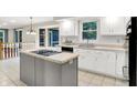 Bright kitchen featuring white cabinets, tile countertops, an island cooktop, and stainless appliances at 58 Penn Pl, Zionsville, IN 46077