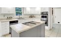 Updated kitchen featuring stainless steel appliances, tile countertops, and a functional island cooktop at 58 Penn Pl, Zionsville, IN 46077