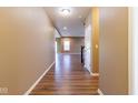 Hallway with hardwood flooring leading to a brightly lit living area and stairwell at 6610 Aberdeen Dr, McCordsville, IN 46055